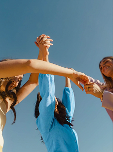Friends joining hands under a blue sky