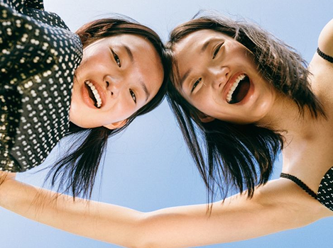 Two young women laughing under a blue sky