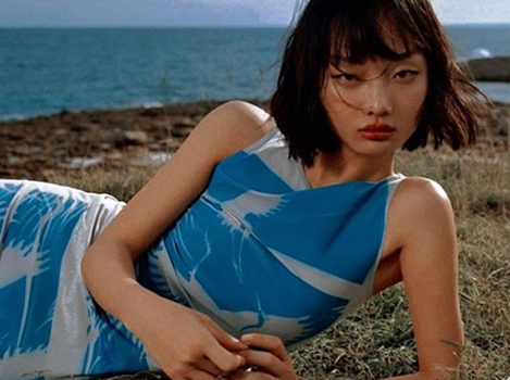 A woman in a blue dress lying by the sea